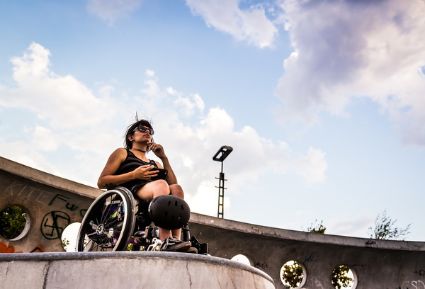 David wird aus der Froschperspektive fotografiert. Er sitzt in seinem Rollstuhl auf einer Skaterrampe.