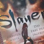 Das Bild zeigt das Cover eines Buches mit dem Titel "Slayer: Das Erbe der Jägerin" von Kiersten White. Es ist aus der Welt von "Buffy". Auf dem Cover ist eine Person mit langen Haaren und dunkler Kleidung abgebildet, die in einer feurigen und rauchigen Umgebung steht. Der Hintergrund ist dramatisch und düster gestaltet. Das Buch liegt auf einem lila Untergrund, umgeben von mehreren kleinen, bunten Kerzen und einigen Herbstblättern.